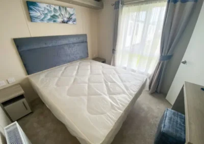 Caravan bedroom with double bed and patterned headboard - West Point Beach Resort