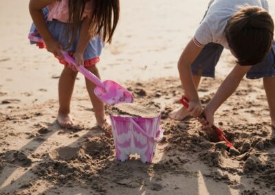 Children digging in the sand with pink bucket on the beach - West Point Beach Resort