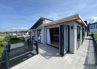 Lodge exterior decking with glass balustrade and sea view - West Point Beach Resort