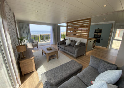 Lodge lounge with grey corner sofa and partition wall - West Point Beach Resort